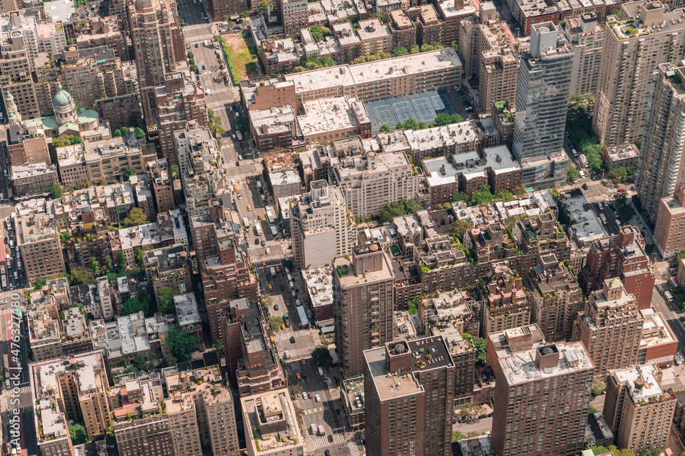 Fototapeta premium Aerial top view of New York City building roofs. Bird's eye view from helicopter of cityscape metropolis infrastructure, traffic, residential district and yellow cabs moving along streets and avenues