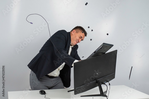 Fotografia Caucasian man in a suit gets angry and smashes the keyboard on the monitor