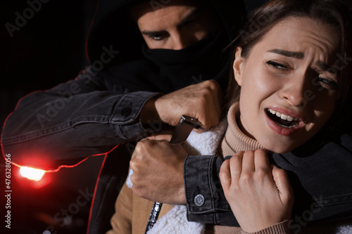 Fotografija Criminal with knife attacking young woman outdoors at night