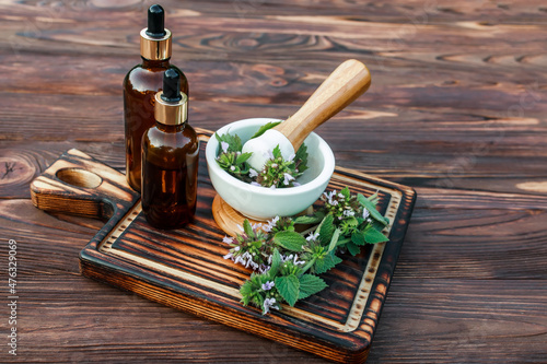 Lamium album, white nettle or white dead-nettle Flowers in mortar. Preparation of elixirs from medicinal herbs by herbalists. Essential oil in pharmacy bottle with pipette at cosmetologist in salon.