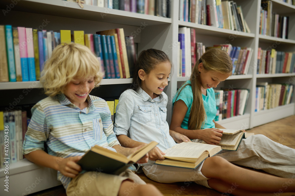 Boy and two girls sitting on floor reading books Boy and two girls sitting on floor reading books