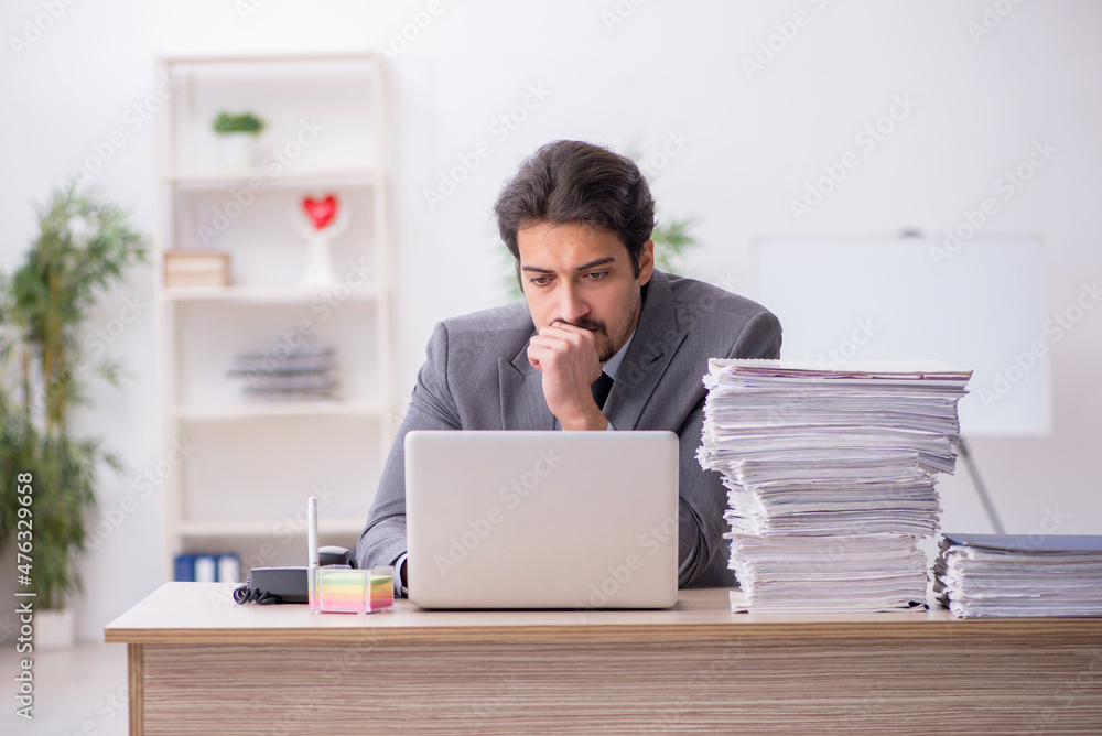 Young male employee and too much work in the office Young male employee and too much work in the office