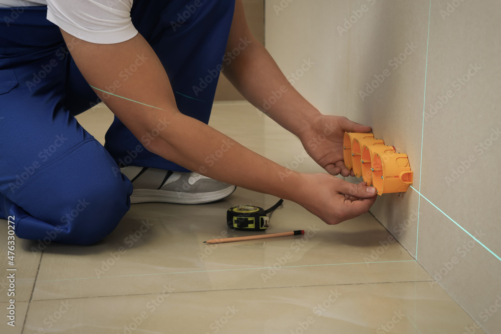 Worker using cross line laser level for installation of outlet box in plasterboard, closeup Worker using cross line laser level for installation of outlet box in plasterboard, closeup