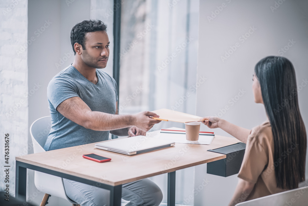 Girl gives guy folder with documents Girl gives guy folder with documents