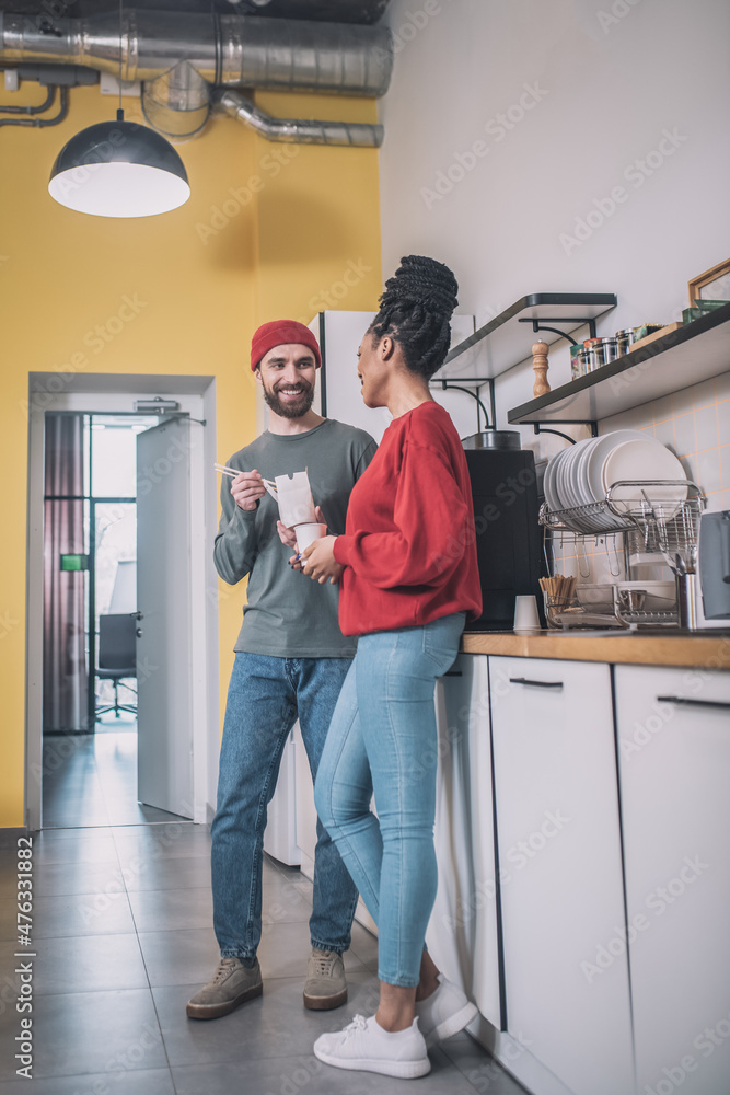 Guy and girl communicating in office kitchen