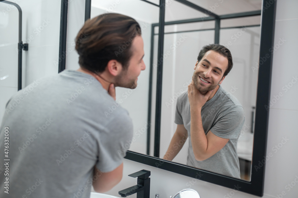 Man near the mirror scrutinizing himself Man near the mirror scrutinizing himself