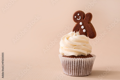 Tasty Christmas cupcake with gingerbread cookie on beige background