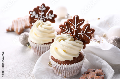 Tasty Christmas cupcakes with gingerbread cookies on light background