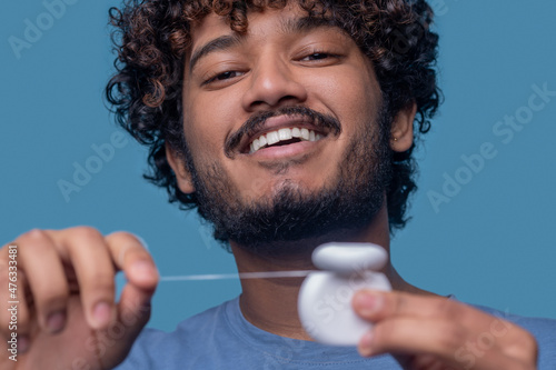 Dark-haired man smiling at the camera before the flossing procedure