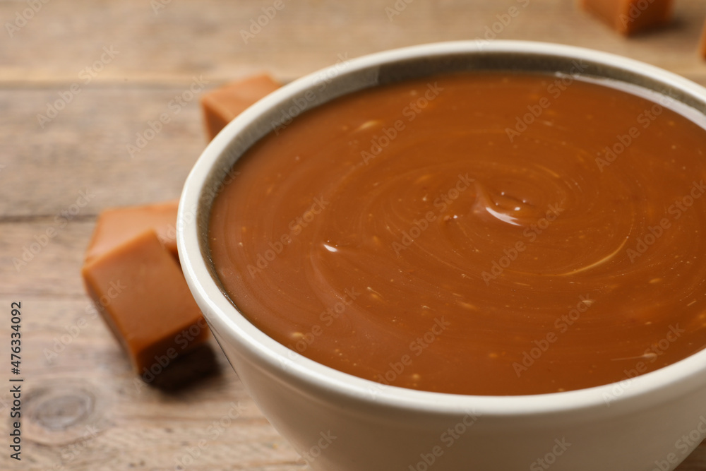 Yummy salted caramel in bowl on wooden table, closeup Yummy salted caramel in bowl on wooden table, closeup