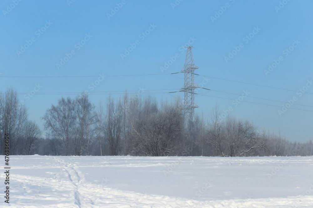 Winter landscape. Snow in the foreground, power lines and a grove of trees in the distance. Cool colors, blue shades. Winter landscape. Snow in the foreground, power lines and a grove of trees in the distance. Cool colors, blue shades.