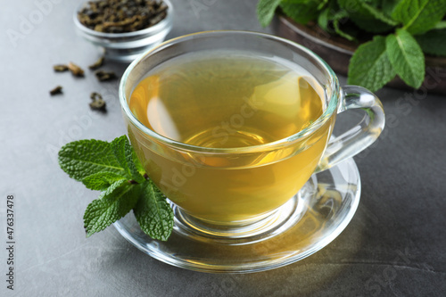 Cup of hot aromatic mint tea on grey table, closeup