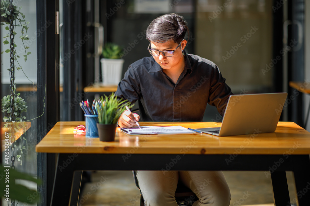 Asian Handsome young smiling businessman working with documents in the office Asian Handsome young smiling businessman working with documents in the office