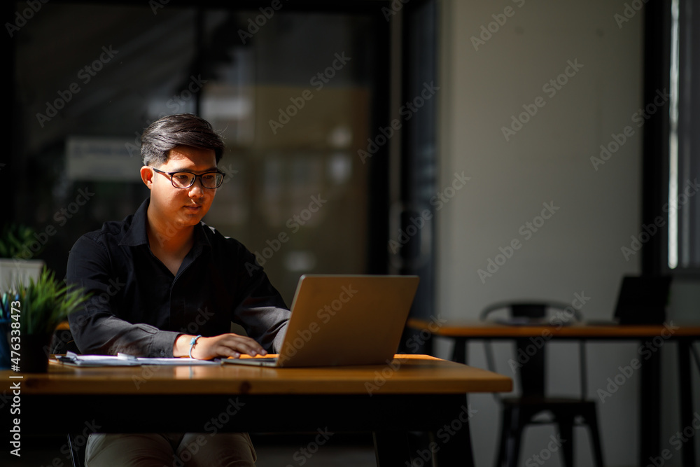 Asian Handsome young smiling businessman working with documents in the office Asian Handsome young smiling businessman working with documents in the office