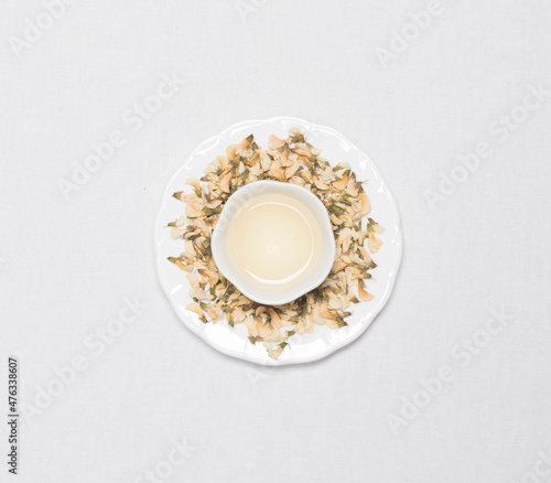 a cup of flower tea with dried flower tea leaves around