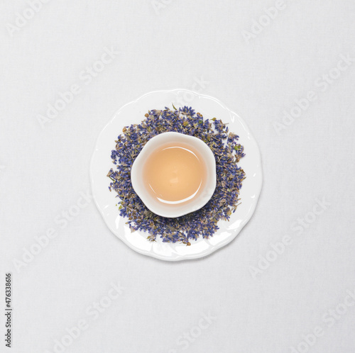 a cup of flower tea with dried flower tea leaves around