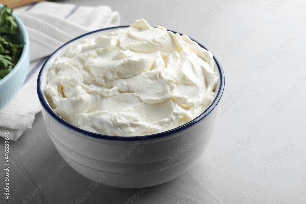 Bowl of tasty cream cheese on grey table Bowl of tasty cream cheese on grey table