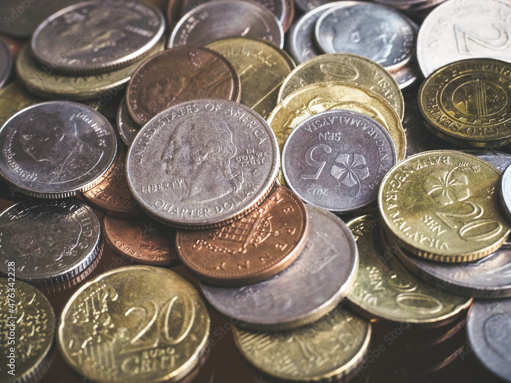 Close up shot of various currency coins with light faded and dark tone with contrast, focus on dollar coin Close up shot of various currency coins with light faded and dark tone with contrast, focus on dollar coin