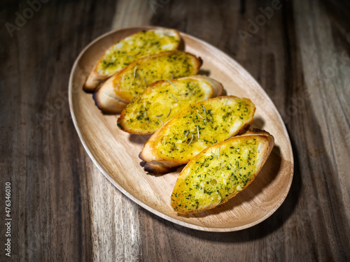 Slices of garlic bread , cheese and herbs on wooden table , top view.