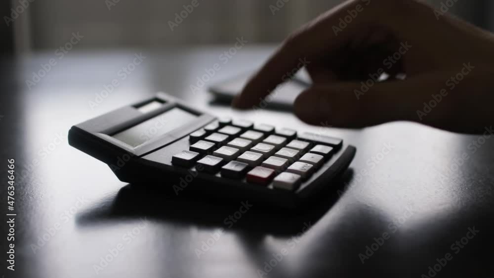 Hand of a businessman using a calculator and taking notes in notepad Hand of a businessman using a calculator and taking notes in notepad