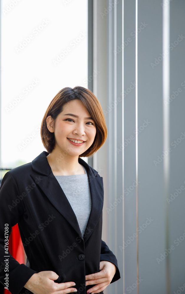 Portrait close up studio shot of Asian young happy short hair female cheerful millennial businesswoman blogger vlogger freelancer influencer in formal suit smiling look at camera in office building Portrait close up studio shot of Asian young happy short hair female cheerful millennial businesswoman blogger vlogger freelancer influencer in formal suit smiling look at camera in office building