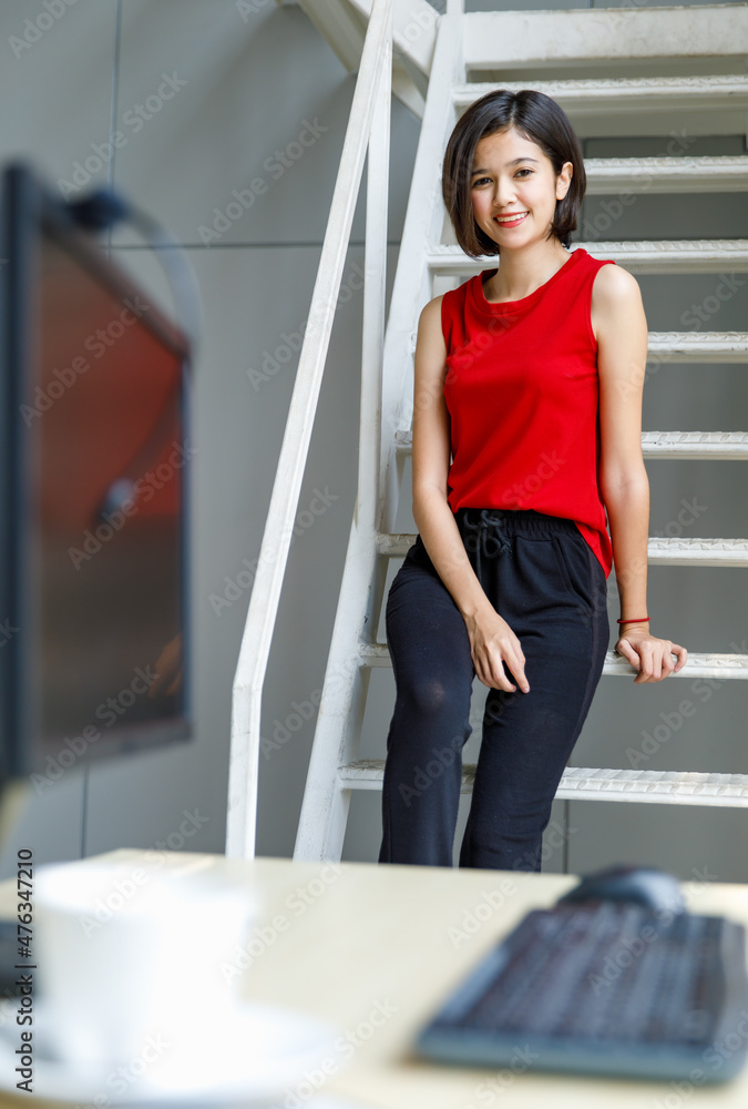 Portrait shot of Asian young happy cheerful millennial short hair teenager female model in red sleeveless shirt and black sweatpants standing crossed arms smiling look at camera on wall background
