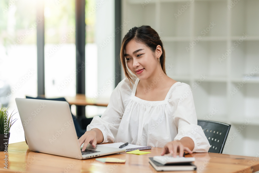 Portrait of smiling beautiful Asian businesswoman enjoy the idea sitting with laptop computer at office. Portrait of smiling beautiful Asian businesswoman enjoy the idea sitting with laptop computer at office.