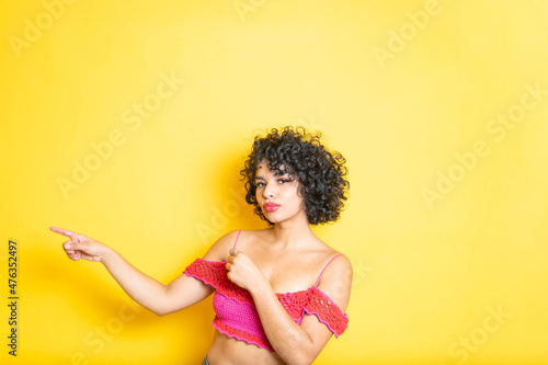 beautiful curly haired mexican young woman pointing up with both hands
