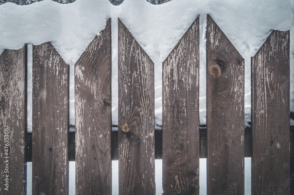 An old wooden picket fence in the village in winter. Snow on the fence. Selective focus An old wooden picket fence in the village in winter. Snow on the fence. Selective focus
