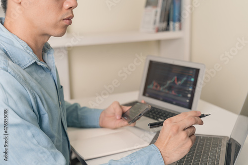 Trader, investor, business man is using laptop, smart phone to trading, investment on stock market, Cryptocurrency as Bitcoin with technical price graph, Cryptocurrency or stock market trading chart.