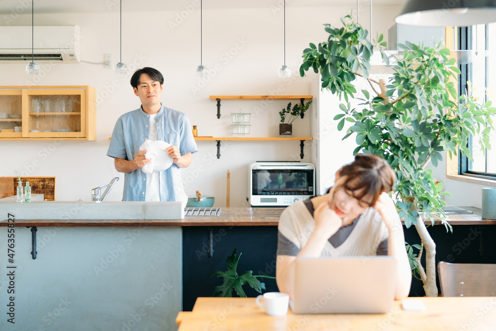 仕事で疲労する女性と家事をする男性(心配)
仕事で疲労する女性と家事をする男性(心配)