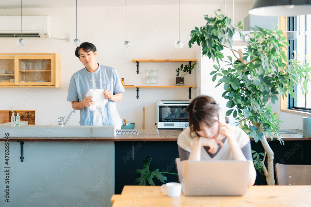 仕事で疲労する女性と家事をする男性(心配)
仕事で疲労する女性と家事をする男性(心配)