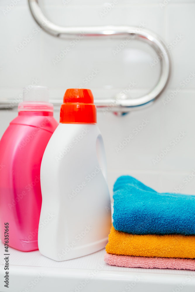 Two bottles of laundry detergent and colorful towels on the washing machine. Two bottles of laundry detergent and colorful towels on the washing machine.