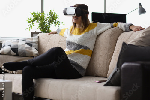 Female sit on couch wear vr glasses modern device at home and enjoy spare time