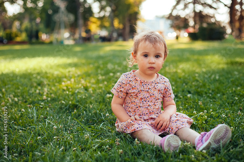 child sitting in the park and playing with the grass. green life concept 
