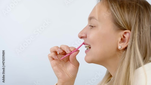 Oral care concept with braces. Cleaning braces teeth system, close-up. Woman brushing metal brackets by orthodontic toothbrushes, dental floss, monobuched brush. Healthcare hygiene. 