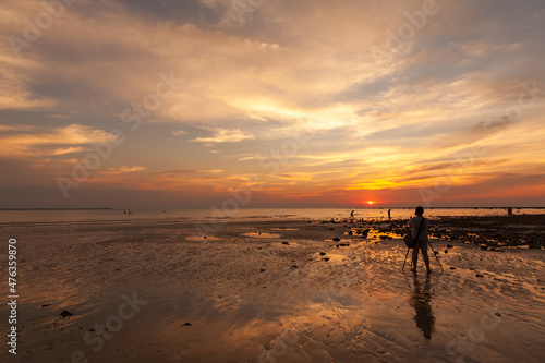 female amateur photographer Taking sunset pictures on the beach