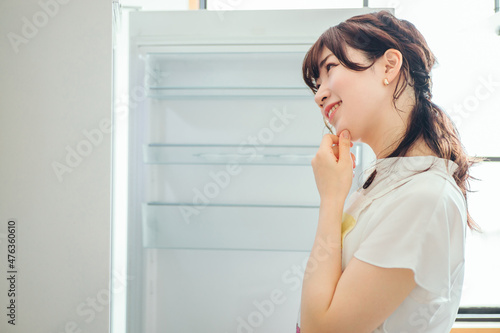 何も入ってない冷蔵庫を見る女性 