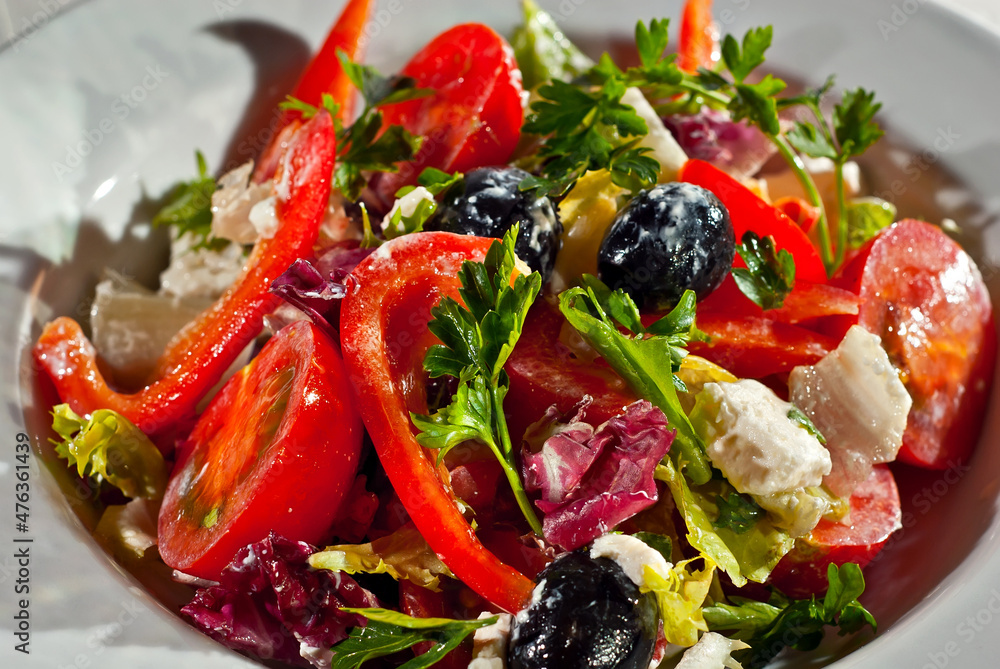 Salad with tomatoes, peppers, olives, cheese and cabbage. Fresh salad in a white plate on a light background. Salad with tomatoes, peppers, olives, cheese and cabbage. Fresh salad in a white plate on a light background.