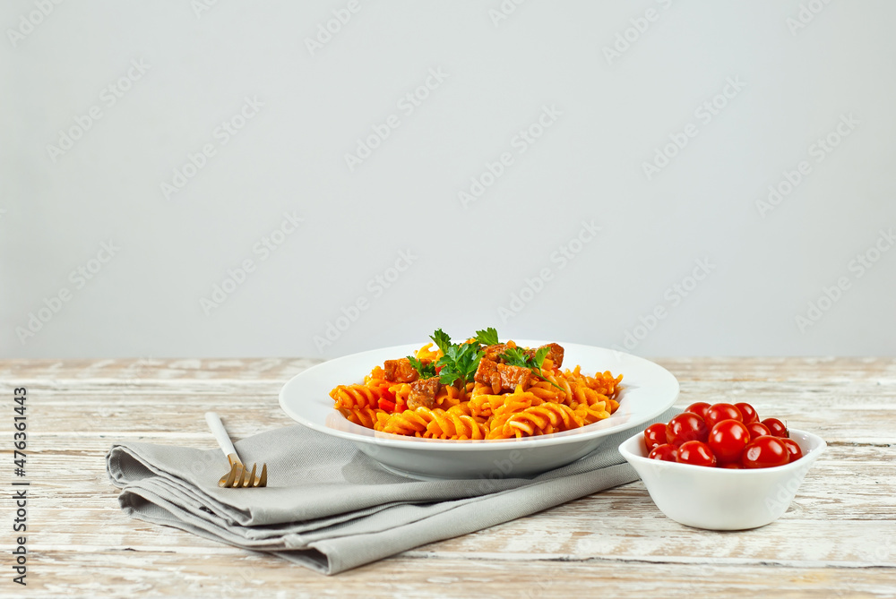 Pasta with meat and tomatoes in a white plate. Pasta on a shabby wooden table. Copy space and free space for text near food. Pasta with meat and tomatoes in a white plate. Pasta on a shabby wooden table. Copy space and free space for text near food.