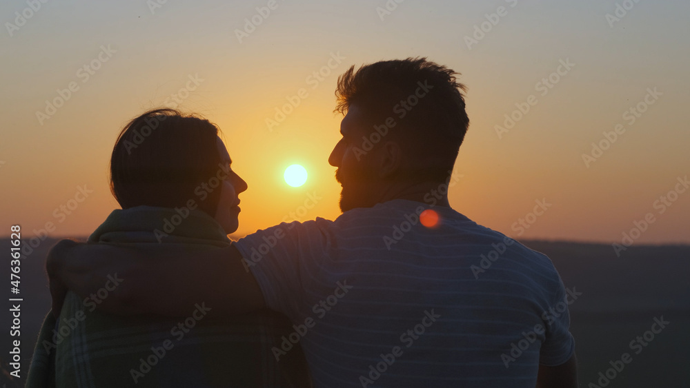 The romantic couple sitting on mountain top on sunset background