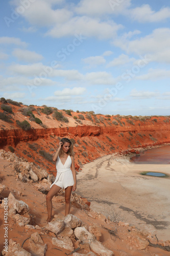 Woman in white dress looking at the cliff with red sandy beach on Australia