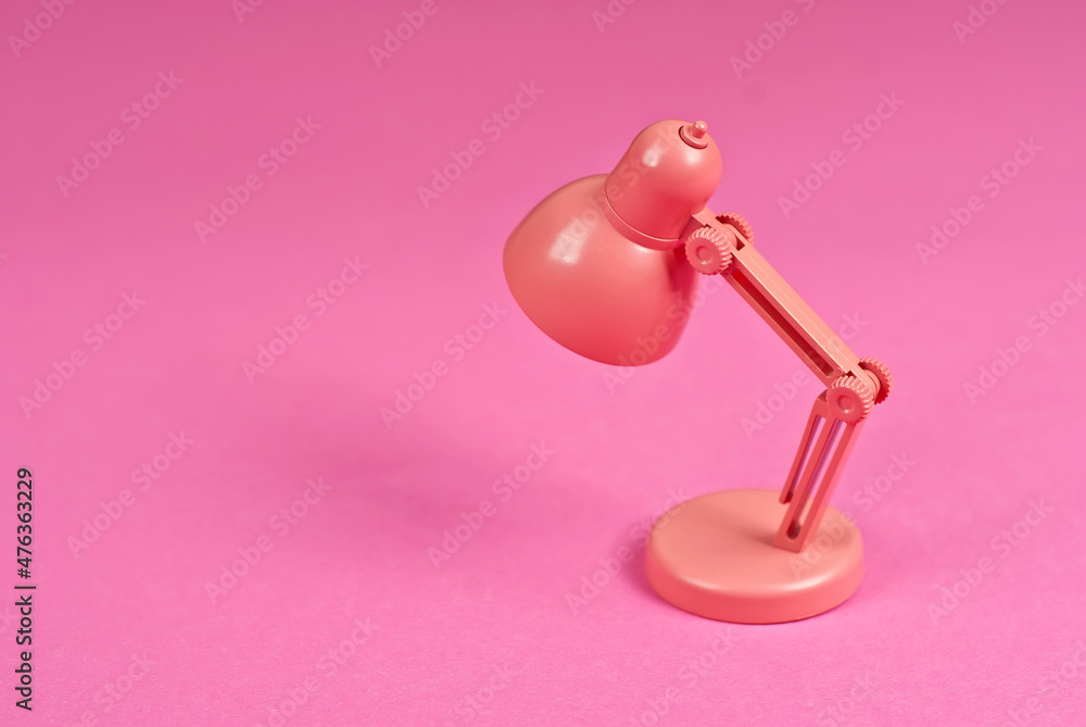 Pink lamp on a background of papers. Toy table lamp. Copy space and free space for text near the lamp. The concept of roochy space and creative ideas. Pink lamp on a background of papers. Toy table lamp. Copy space and free space for text near the lamp. The concept of roochy space and creative ideas.