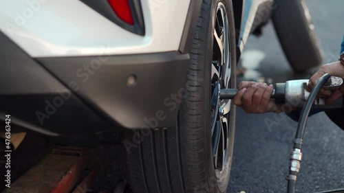 mechanic man using an electric drill to loosen the bolts of vehicle wheel for changing a car tire