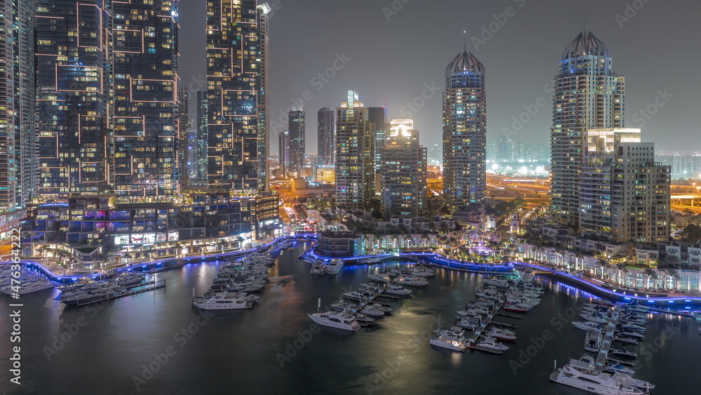 Dubai Marina luxury tourist district with skyscrapers and towers around canal aerial night timelapse