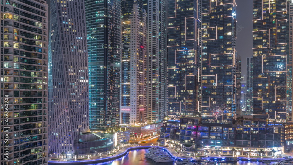 Dubai Marina luxury tourist district with skyscrapers and towers around canal aerial all night timelapse