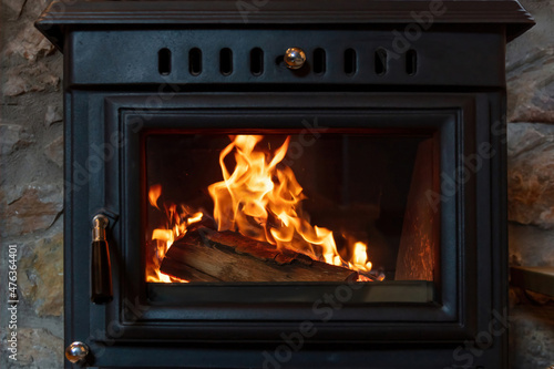 Bilde på lerret Burning fire in a wood stove fireplace radiates heat, warm home interior,