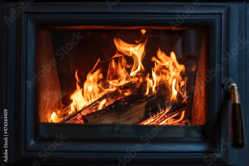 Burning fire in a wood stove fireplace radiates heat  warm home interior 