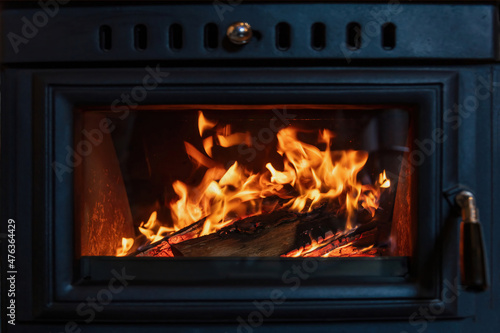 Burning fire in a wood stove fireplace radiates heat  warm home interior 