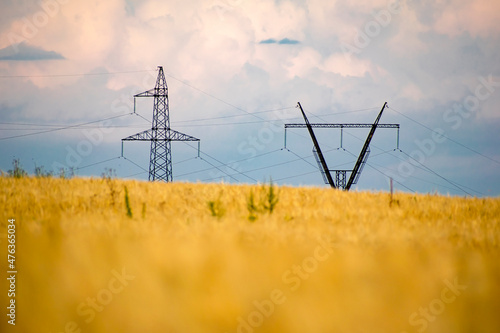 Steel towers of power lines on the background of a wheat field. Technological concept.